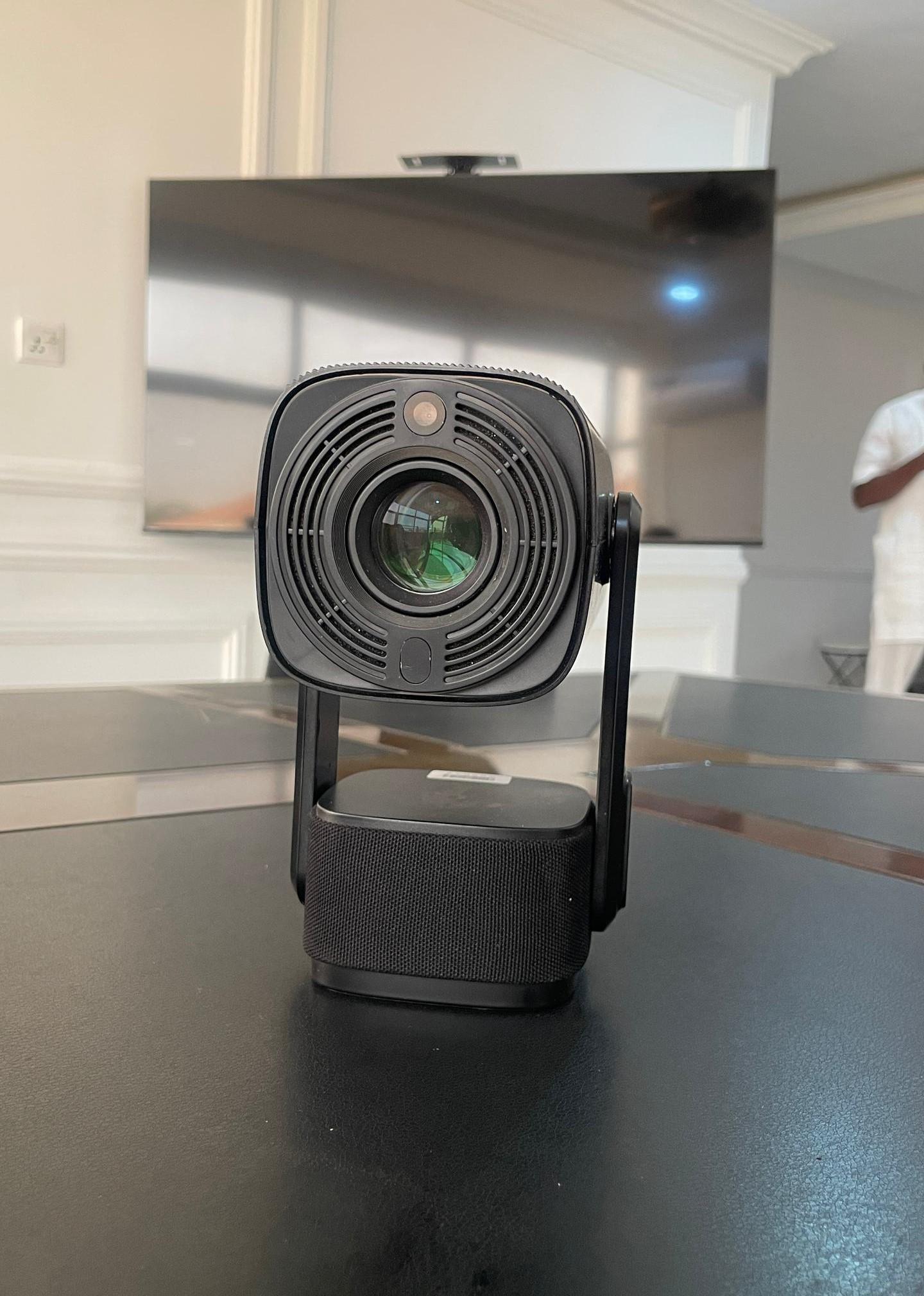 Front view of the Diyaa projector: a black solar-powered learning device with a large lens, cooling vents and a fabric-covered speaker base